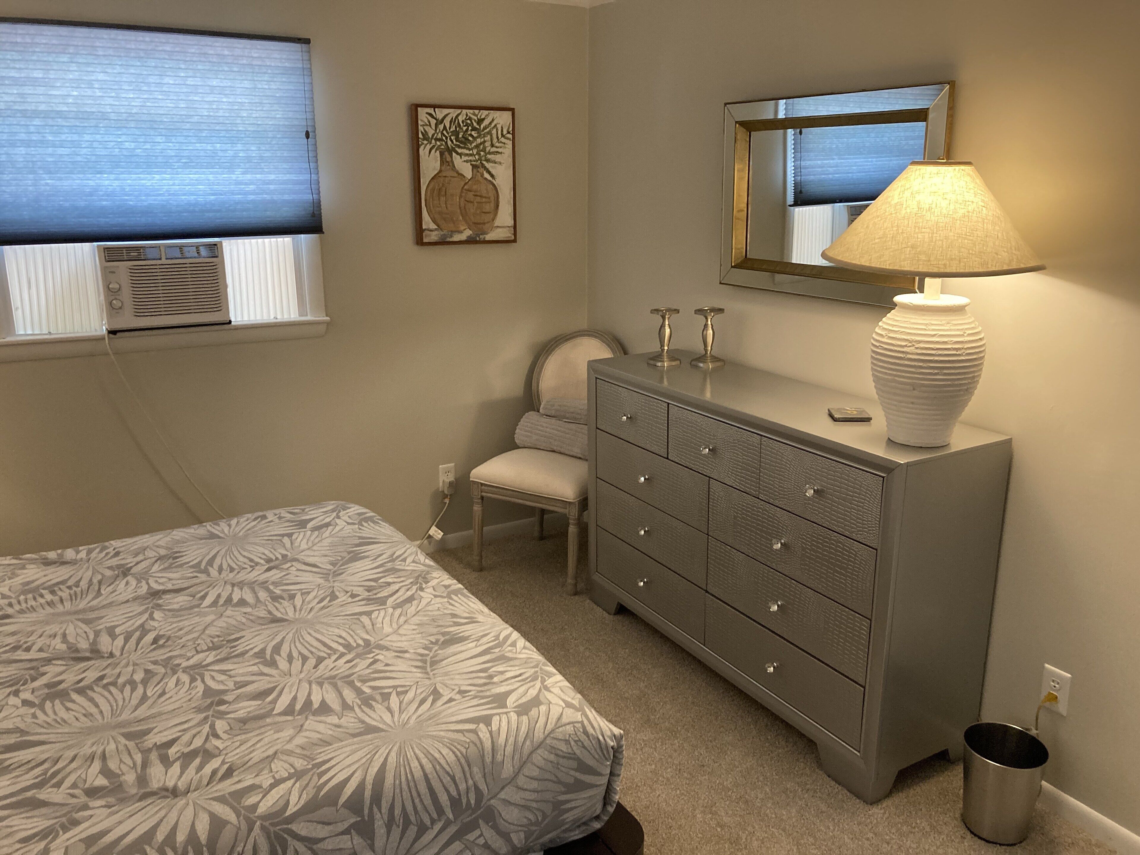 A bedroom with a bed, dresser, chair, and a mirror.