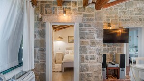 Une pièce aux murs de pierre, avec un lit, un téléviseur et une petite table équipée de haut-parleurs.