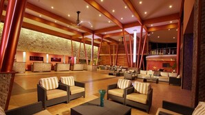 A spacious lobby with multiple seating areas, a reception desk, and a high ceiling with exposed beams.