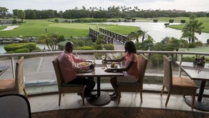 A dining area with a view of a golf course and a river.