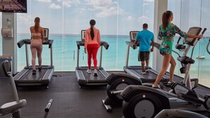 A gym with treadmills and exercise equipment, overlooking a body of water.