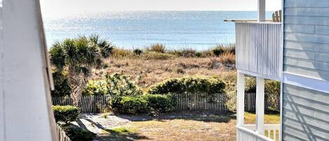 Blick auf ein Anwesen am Strand mit eingezäunter Garten und einer Holzterrasse.