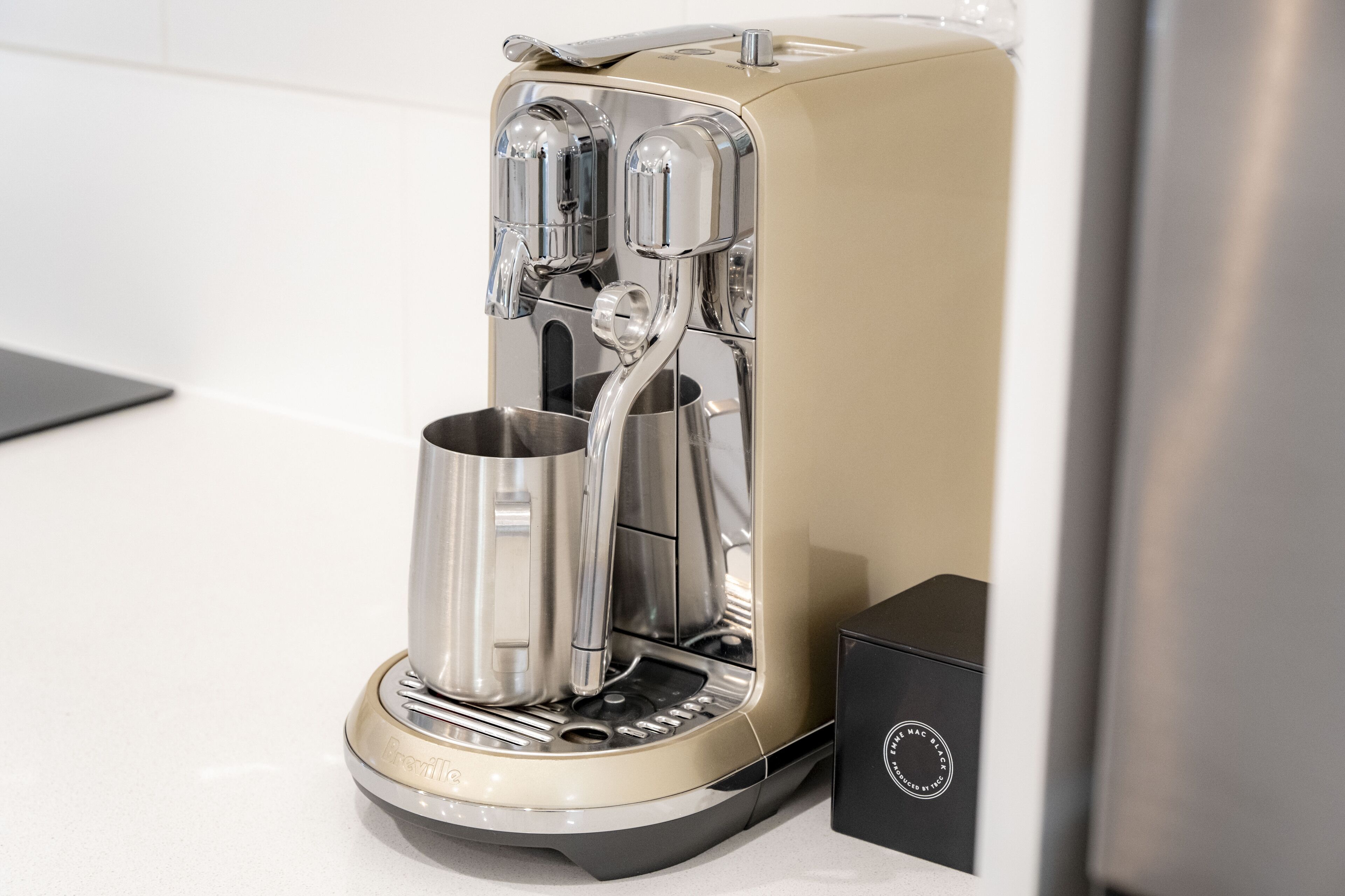 A coffee machine with a sleek, modern design, featuring a metallic finish and a control panel.