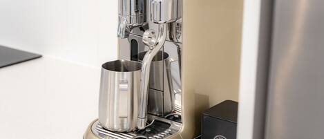 A coffee machine with a sleek, modern design, featuring a metallic finish and a control panel.
