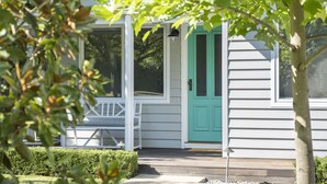 A white house with a green door, a porch, and a small table.