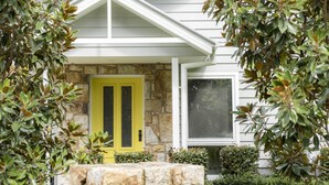 Una casa con cimientos de piedra, una puerta amarilla y fachada blanca.