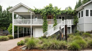A two-story house with a covered porch, a staircase, and a garden with various plants. - Autumn Home, Our Place at Bright - Boasting commanding views of the surrounding landscape from the generous indoor/outdoor living spaces. (Bright)