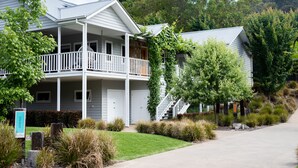 A two-story building with a balcony, a stone foundation, and a well-maintained lawn. - Autumn Home, Our Place at Bright - Boasting commanding views of the surrounding landscape from the generous indoor/outdoor living spaces. (Bright)