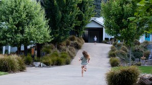 A residential street with houses, a driveway, and a person running.