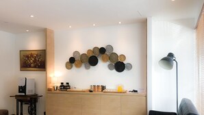 Una sala de estar moderna con un sofá, una cafetera, una lámpara y un adorno de pared.