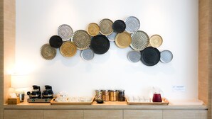 Una cocina moderna con una composición decorativa de platos circulares en la pared, una estación de café y un lavamanos con un cartel.