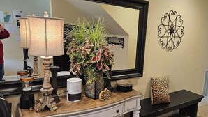A well-lit room with a large mirror, decorative wall art, a vase with green plants, and a bench with a leopard print pillow. - 3 Master Suites, Spa, Pool table, Game room, views (Tillamook)