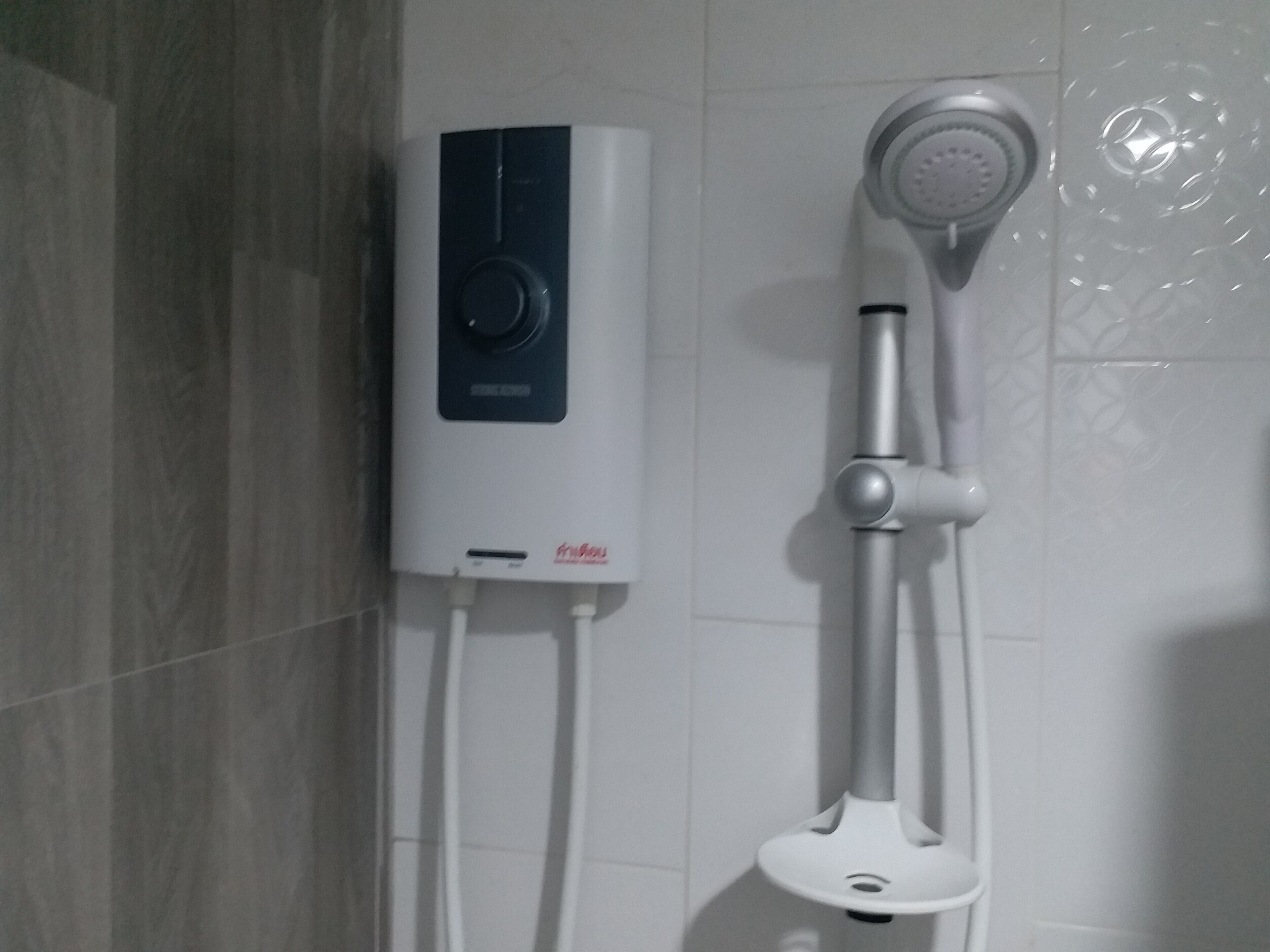 A modern bathroom with a built-in water heater, a handheld showerhead, and a wall-mounted faucet.