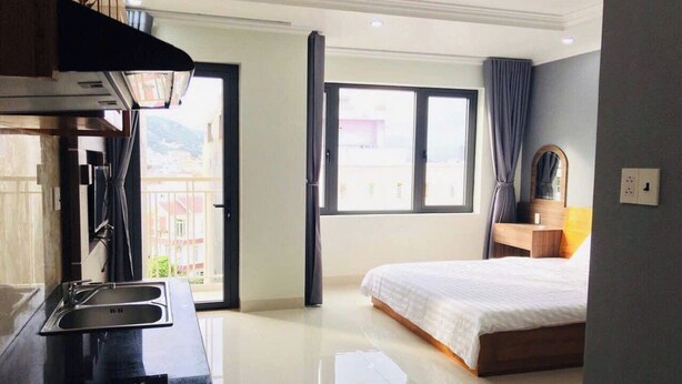 A hotel room with a bed, a window, a sink, and a mirror. - Nhat Thu Hotel & Apartment (Ho Chi Minh City)