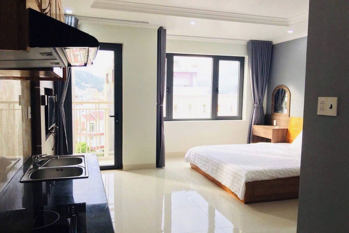 A hotel room with a bed, a window, a sink, and a mirror.