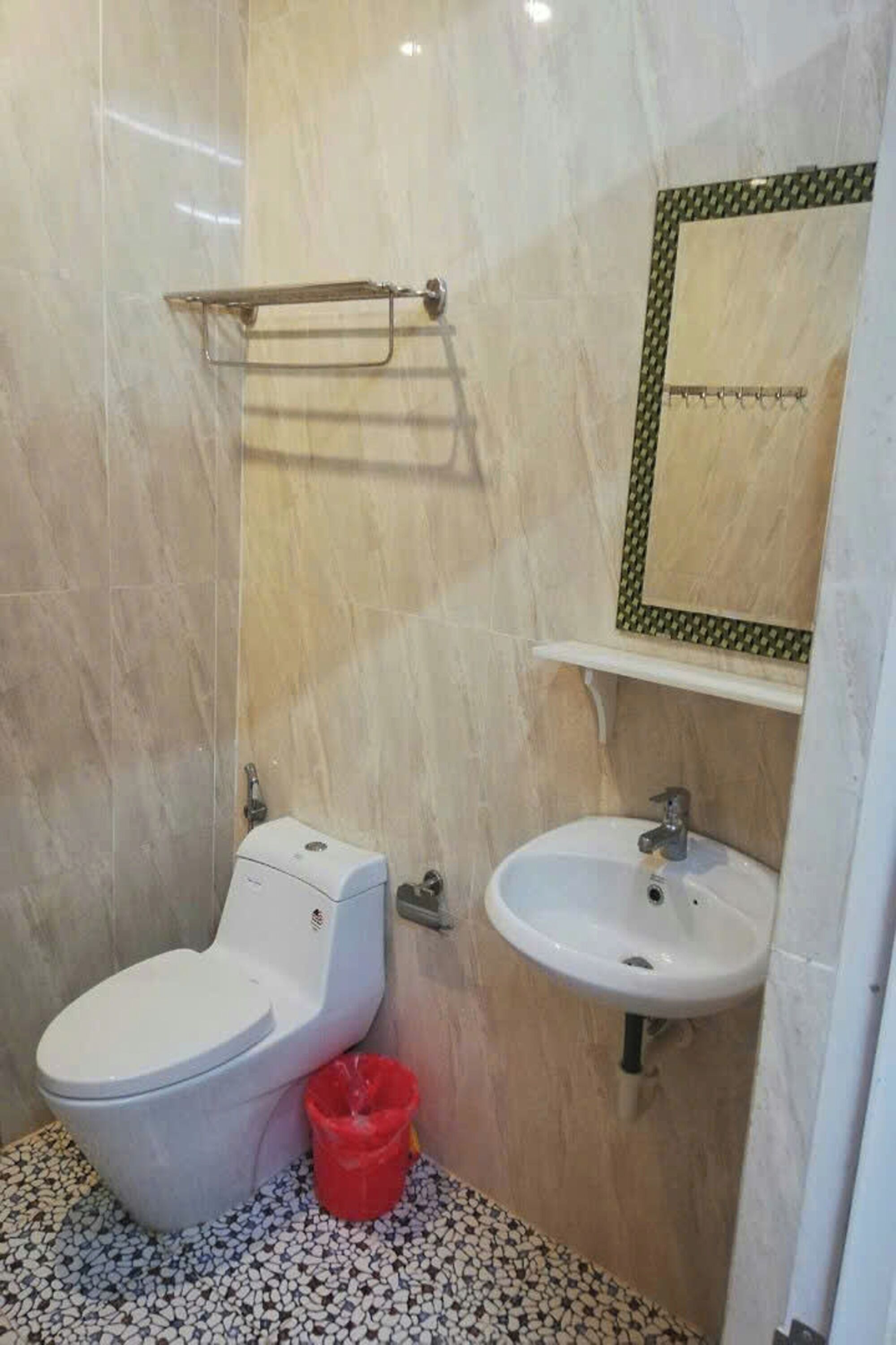 A bathroom with a toilet, sink, and a mirror with a decorative frame.