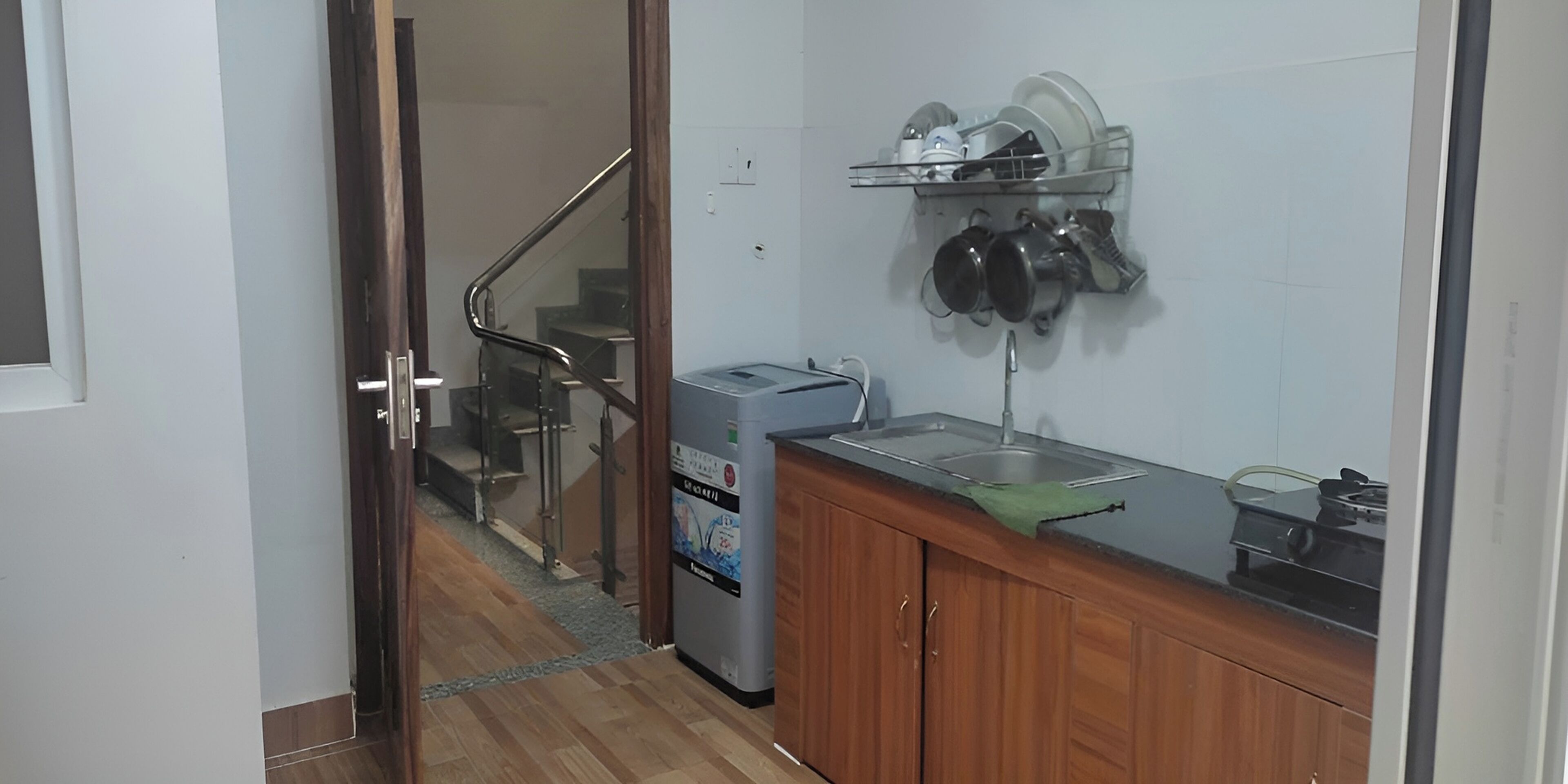A kitchen with wooden cabinets, a countertop, a dish rack, and a refrigerator.