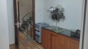A kitchen with wooden cabinets, a countertop, a dish rack, and a refrigerator. - Nhat Thu Hotel & Apartment (Ho Chi Minh City)