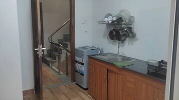 A kitchen with wooden cabinets, a countertop, a dish rack, and a refrigerator.