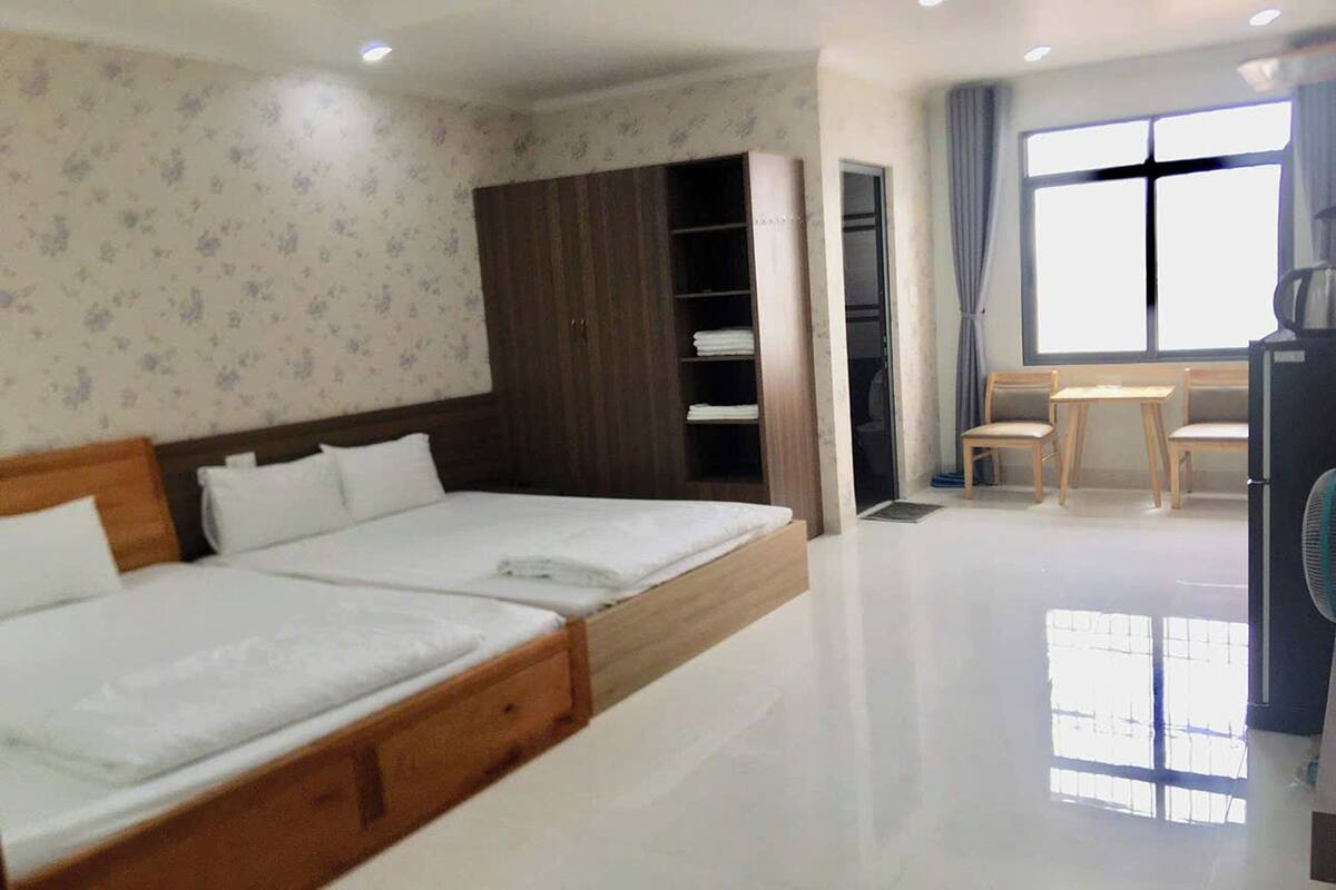 A hotel room with a bed, wardrobe, and a small table with chairs.