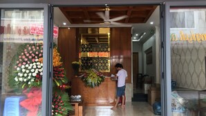 A reception desk with a man standing in front of it, a large floral arrangement, and a sign above the entrance. - Nhat Thu Hotel & Apartment (Ho Chi Minh City)