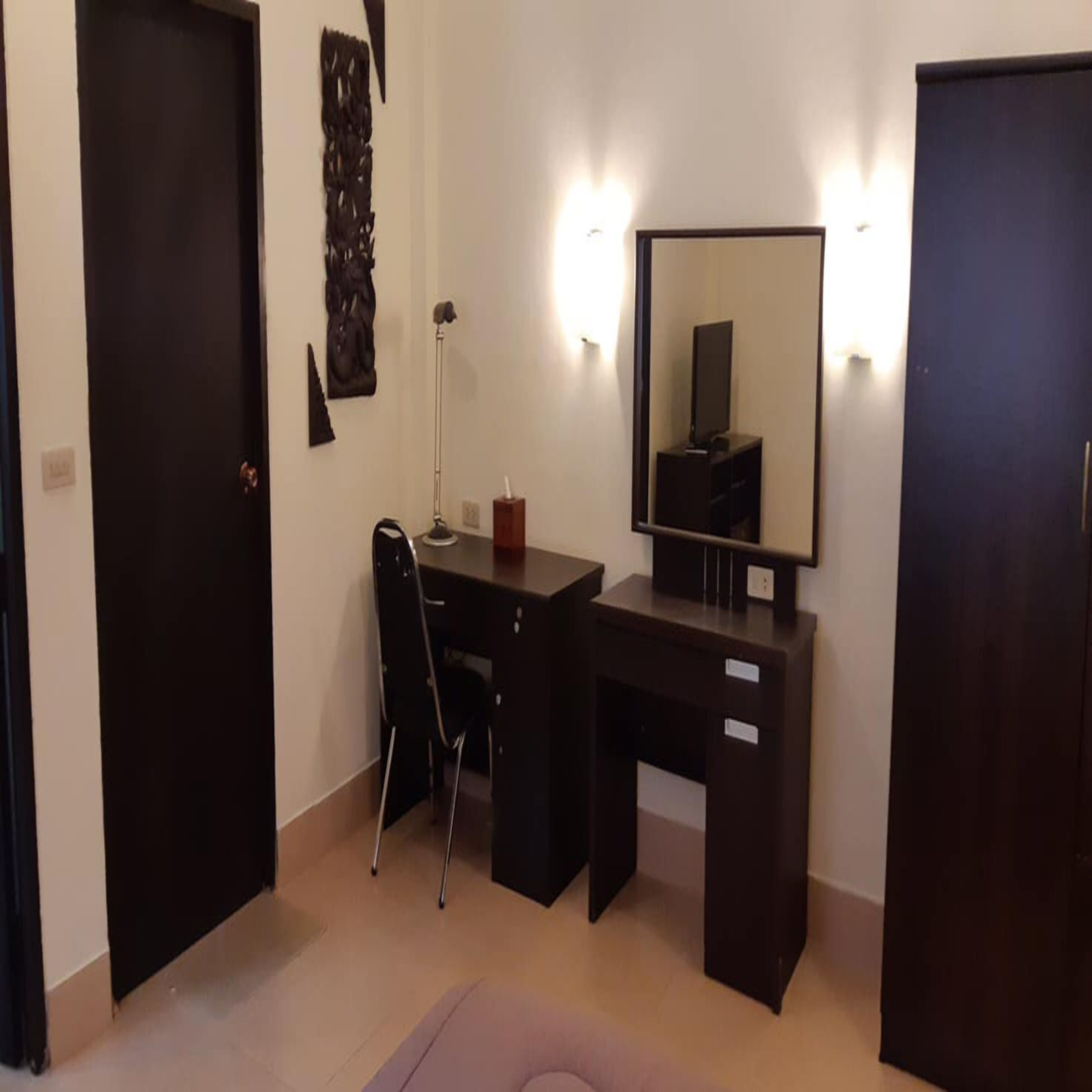 Habitación con escritorio, silla y un espejo grande. Hay una puerta a la izquierda y otra a la derecha.