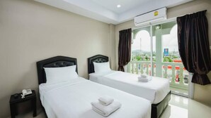 A hotel room with two beds, a small bedside table with a phone, and a balcony with curtains. - Tyler Cherngtalay (Choeng Thale)