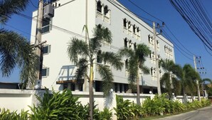 A multi-story building with a white facade, multiple windows, and a sign indicating a restaurant on the ground floor. - Tyler Cherngtalay (Choeng Thale)