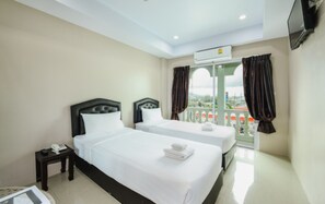 A hotel room with two beds, a small bedside table with a phone, and a balcony with curtains. - Tyler Cherngtalay (Choeng Thale)