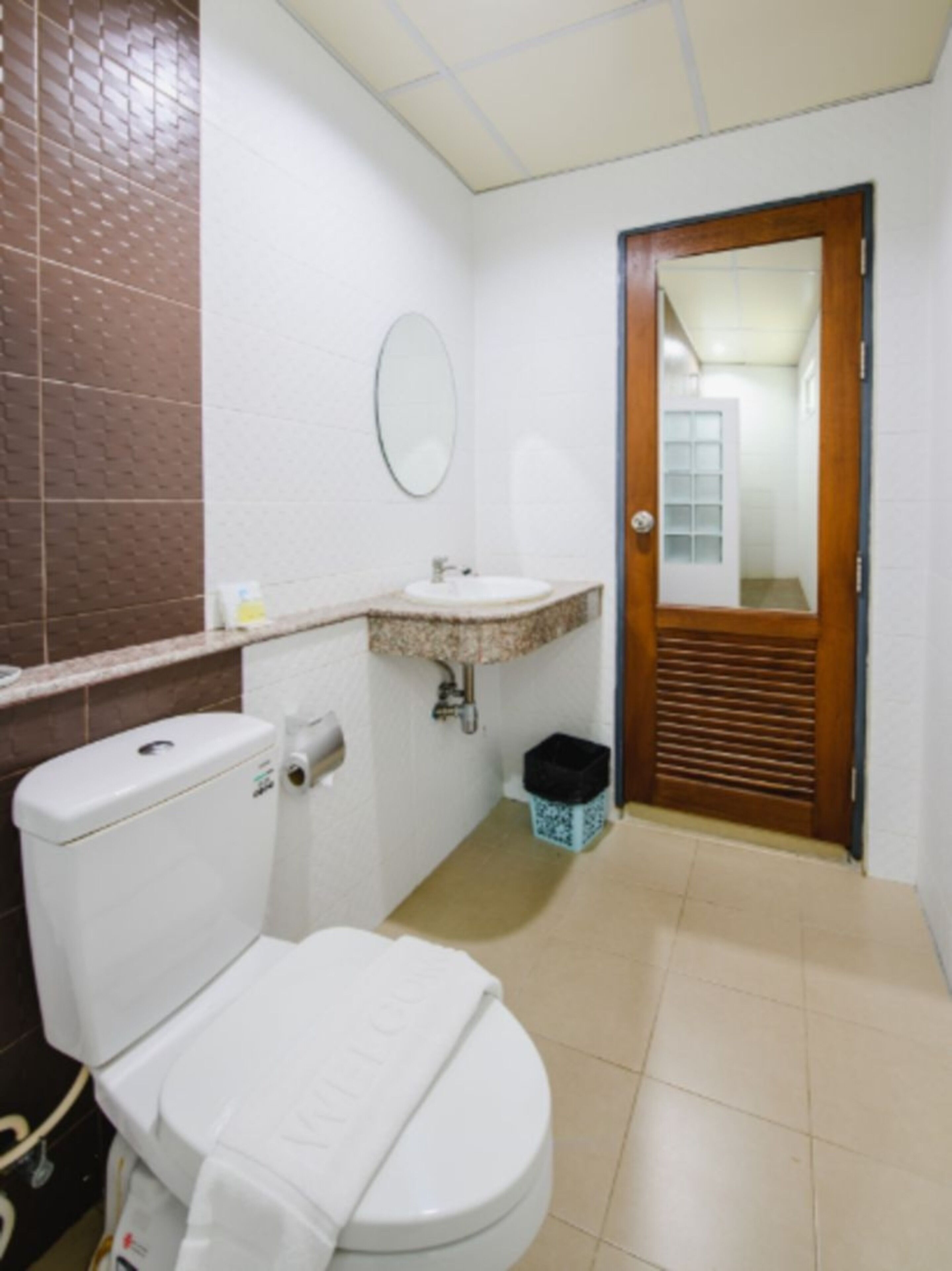 A bathroom with a toilet, sink, and mirror.
