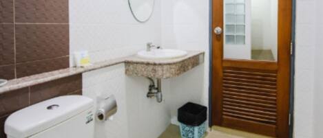 A bathroom with a toilet, sink, and mirror.