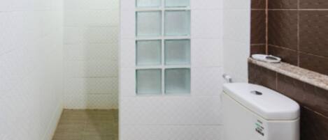 Un baño pequeño y funcional con inodoro blanco, ducha con mampara de vidrio y pared de azulejos marrones.