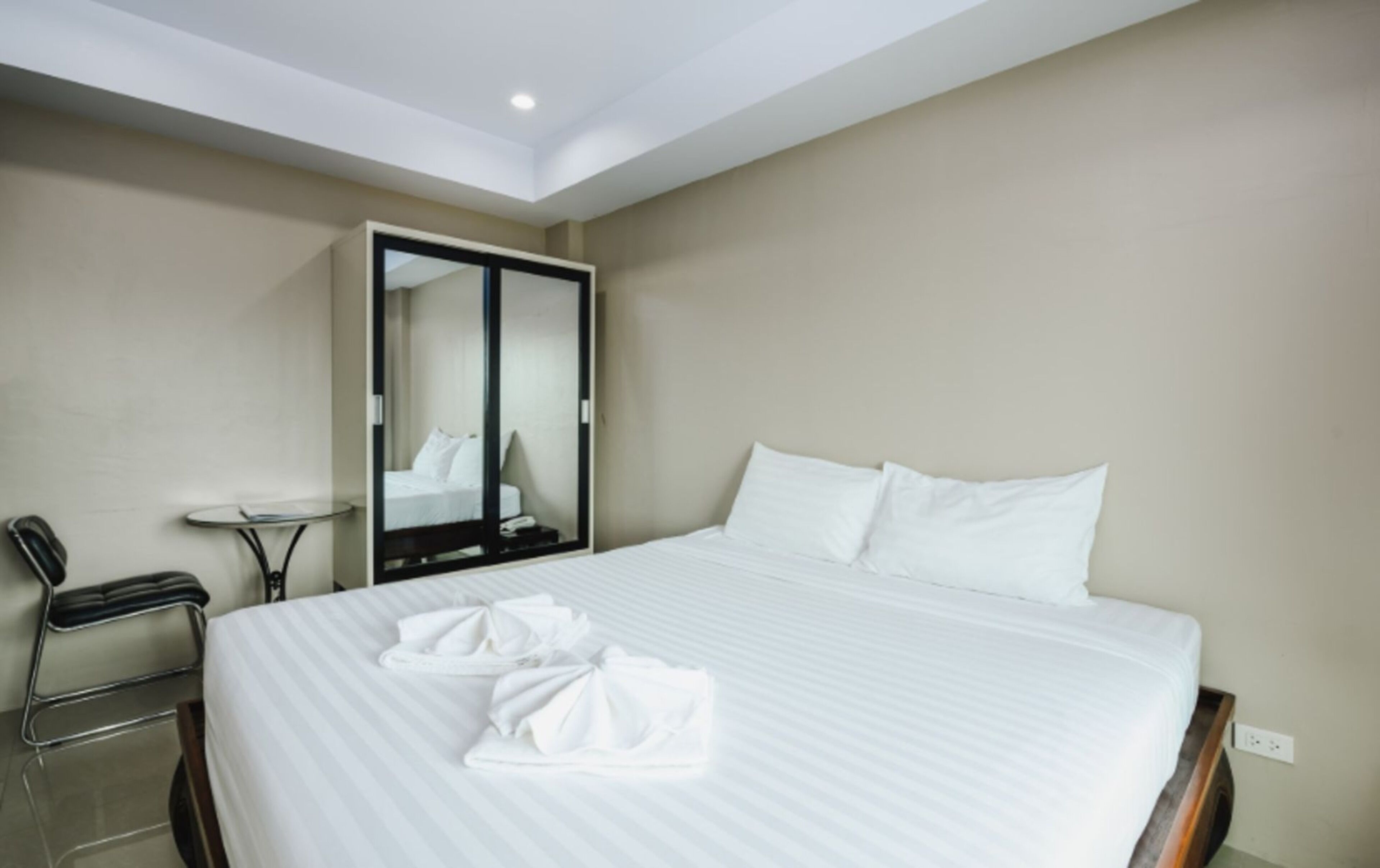 Une chambre d’hôtel avec un grand lit, un miroir, une chaise et une petite table.