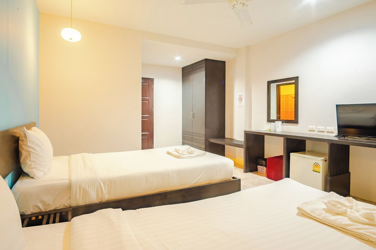 A hotel room with two beds, a desk, a television, and a wardrobe.