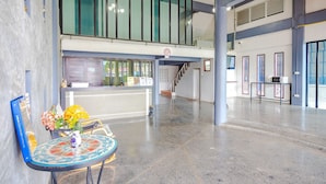 A spacious lobby with a reception desk, a staircase, and a view of the upper floor. - Tyler Banpon (Si Sunthon)
