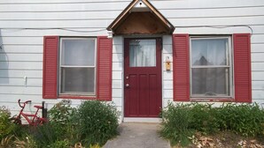 A white house with a red door and shutters, a number 25 mailbox, and a red bicycle leaning against the house. - Escape to the Country! Sleeps 4 (Thomasburg)