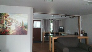 A living room with a sofa, a dining table, and a painting on the wall. - Escape to the Country! Sleeps 4 (Thomasburg)