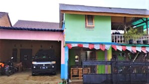 A two-story house with a balcony, a car parked in front, and a gated entrance. - Ijen Miner Guest House (Banyuwangi)