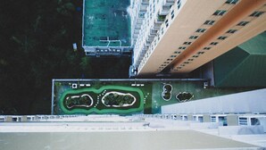 An aerial view of a high-rise building with a rooftop garden, a swimming pool, and a parking area. - Galeri Ciumbuleuit 2 by Nu Apartment (Bandung)
