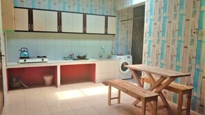 Una cocina compacta con lavadora, hervidor y una mesa con bancos.