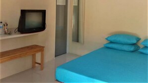 Un dormitorio con una cama, un banco de madera, un televisor y una puerta.