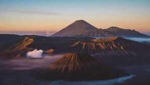 Un paysage volcanique caractérisé par de nombreux cratères et un grand sommet central.