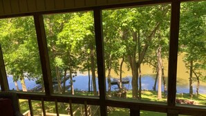 A room with large windows overlooking a lake and trees. - Beautiful Waterfront, w/ Dock, Firepit, Hot tub (Cadiz)