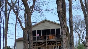 A treehouse with a wooden deck and a small staircase leading up to it, surrounded by trees. - Beautiful Waterfront, w/ Dock, Firepit, Hot tub (Cadiz)
