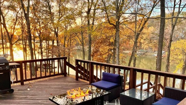 A wooden deck with outdoor seating, a grill, and a view of trees and water. - Beautiful Waterfront, w/ Dock, Firepit, Hot tub (Cadiz)