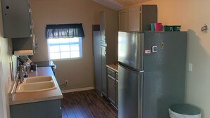 A compact kitchen with a refrigerator, sink, and cabinets.