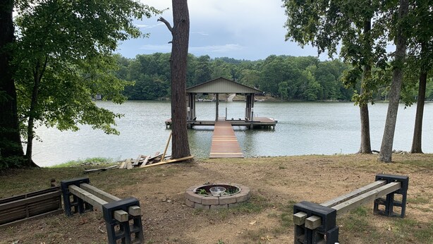 A lakeside deck with a gazebo, fire pit, and benches.