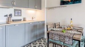 Una cucina moderna con mobili grigi, un piano di lavoro bianco e un'area pranzo con tovaglia fantasia.