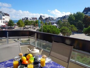 A balcony with a table set for breakfast, overlooking a town with buildings and trees. - Résidence Le Grand Bleu by Interhome (Quiberon)