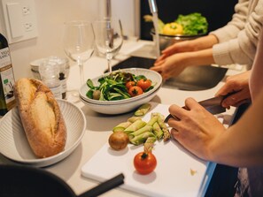 A kitchen counter with a bowl of salad, a loaf of bread, and a cutting board with vegetables. - MIMARU Osaka Namba North (Osaka)